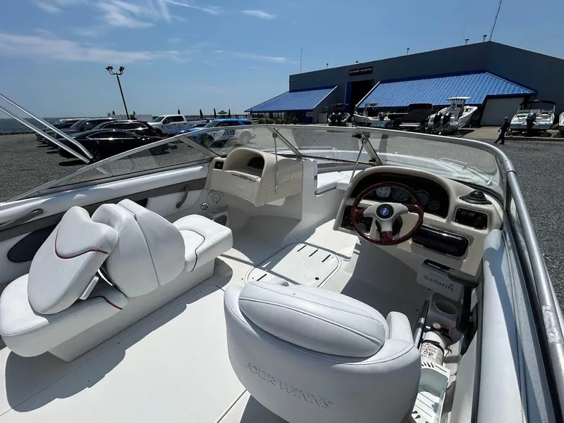 Slide: The Image of 2004 Four Winns 200 Horizon boat interior with white seating and dashboard, parked near a marina. - 7