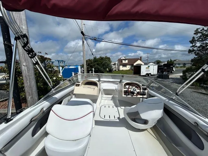 Slide: The Image of 2004 Four Winns 200 Horizon boat interior with seating and steering wheel, under a cloudy sky. - 9