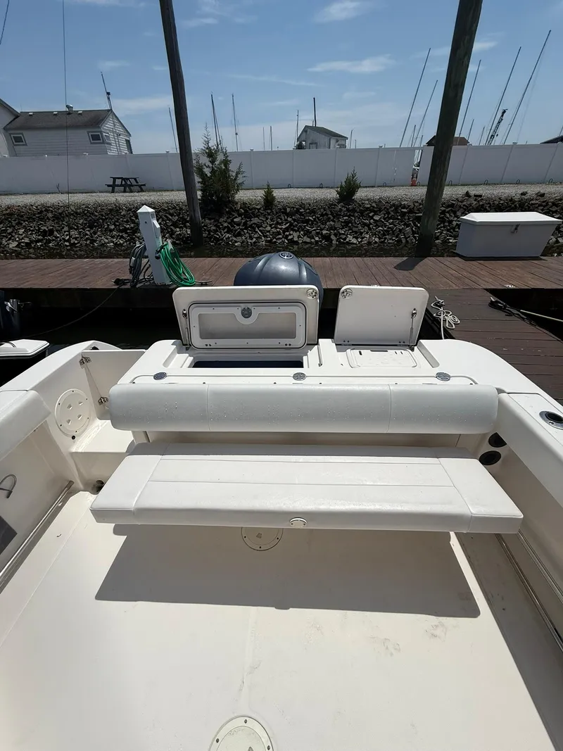 Slide: The Image of 2014 Robalo R245 Walkaround boat interior with seating and storage, docked under clear skies. - 13