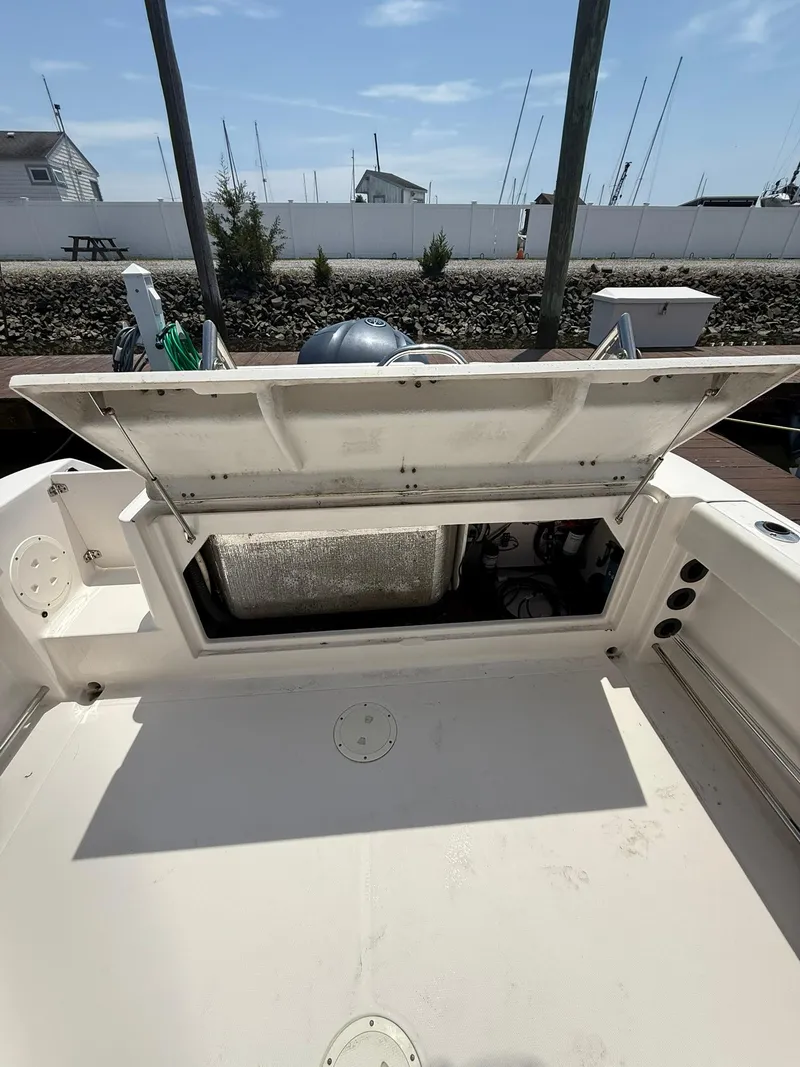 Slide: The Image of 2014 Robalo R245 Walkaround boat with open engine compartment, docked near a marina. - 14