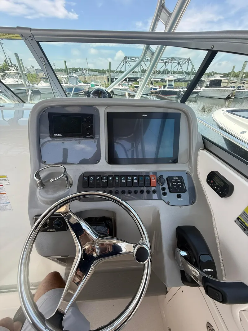 Slide: The Image of 2014 Robalo R245 Walkaround helm with steering wheel, controls, and navigation screens. - 15
