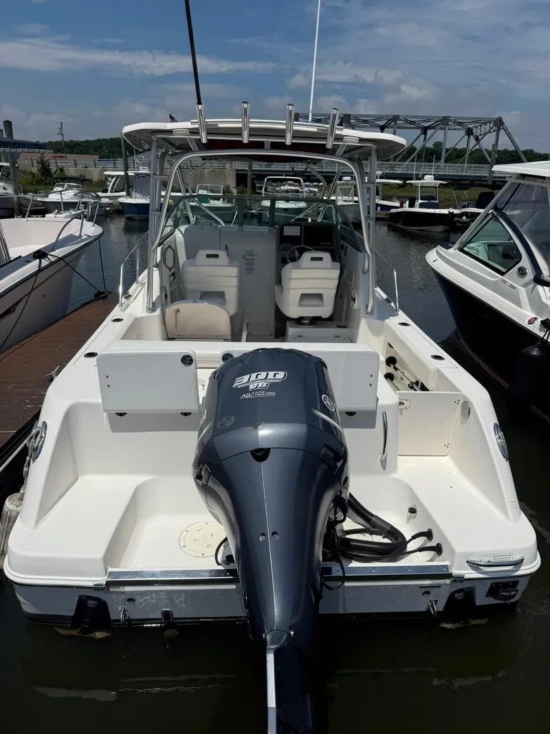 Slide: The Image of 2014 Robalo R245 Walkaround boat docked, featuring a powerful outboard motor. - 2