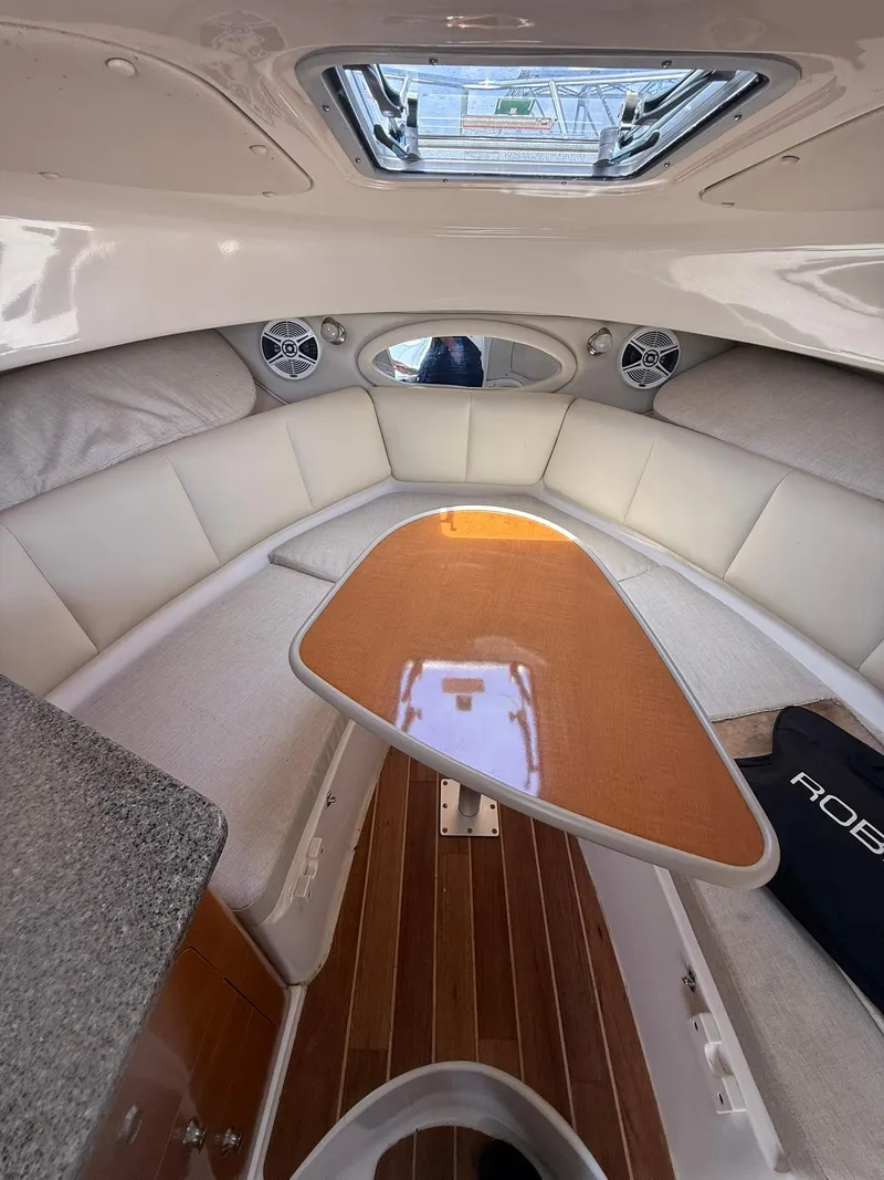 Slide: The Image of 2014 Robalo R245 Walkaround cabin interior with cushioned seating and wooden table. - 4