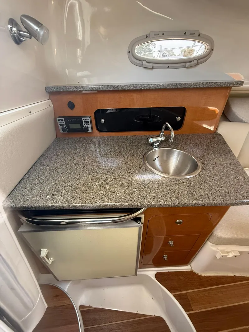 Slide: The Image of 2014 Robalo R245 Walkaround boat interior with kitchenette, sink, and storage drawers. - 5