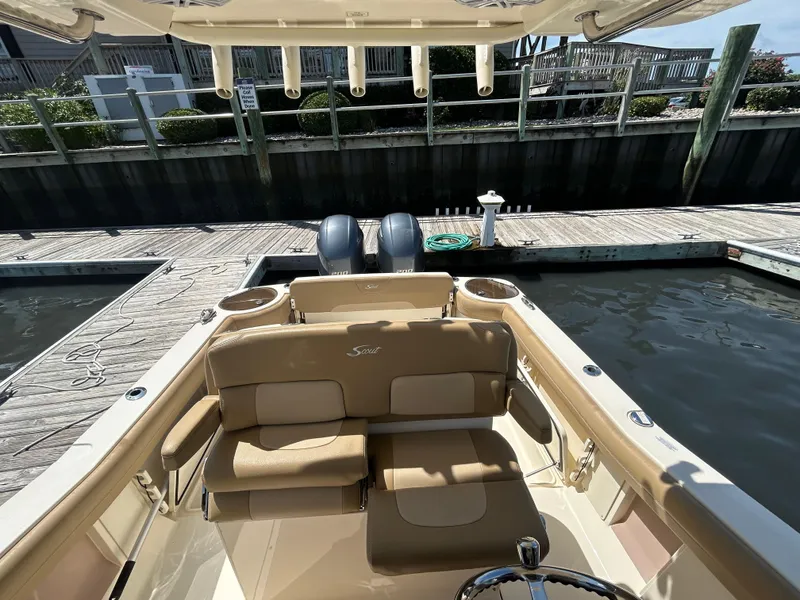 Slide: The Image of 2018 Scout 275 LXF boat docked, featuring tan seating and dual engines. - 20