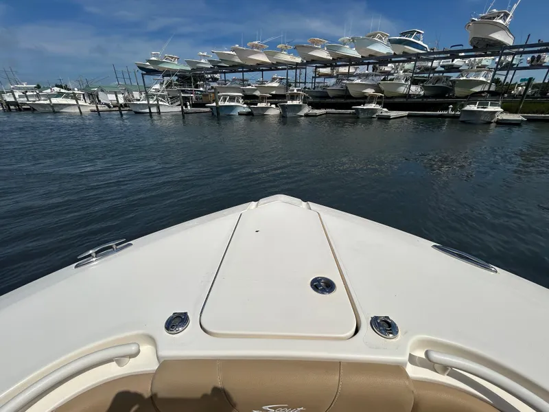 Slide: The Image of Bow view of 2018 Scout 275 LXF boat at marina with stacked vessels. - 23