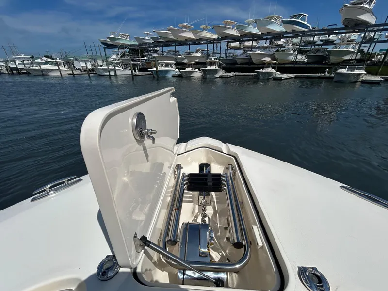 Slide: The Image of 2018 Scout 275 LXF boat with open anchor hatch, docked near stacked boats. - 24