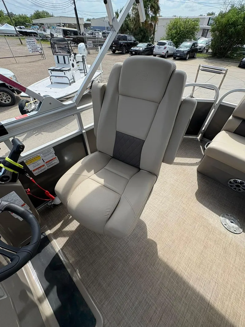 Slide: The Image of 2023 Sun Tracker Party Barge 20 DLX captain's chair, beige upholstery, outdoor setting. - 10