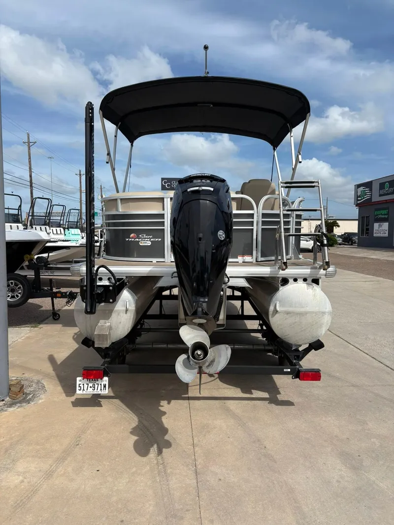 Slide: The Image of 2023 Sun Tracker Party Barge 20 DLX pontoon boat, rear view with motor, parked outdoors. - 16