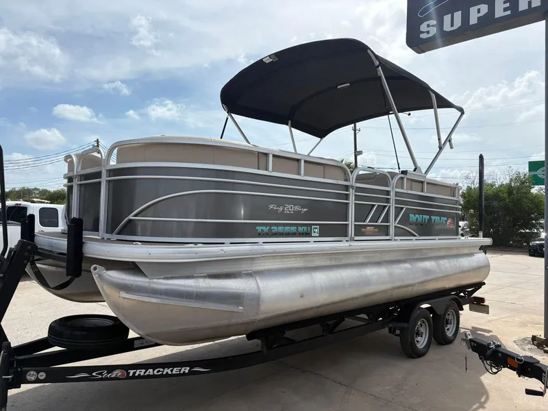 Slide: The Image of 2023 Sun Tracker Party Barge 20 DLX pontoon boat on trailer under a clear sky. - 2