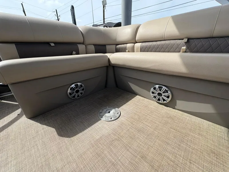 Slide: The Image of 2023 Sun Tracker Party Barge 20 DLX interior with beige seating and built-in speakers. - 6