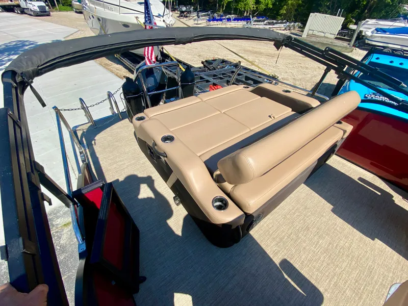 Slide: The Image of 2022 Barletta C24UC pontoon boat with tan seating and cup holders, docked outdoors. - 6