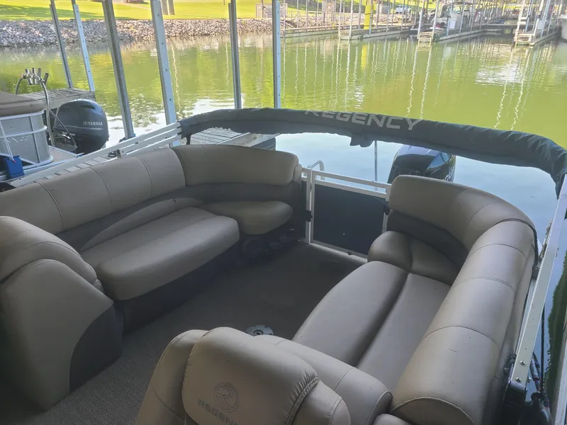 Slide: The Image of 2018 Regency 254 LE3 pontoon boat interior with plush seating at a dock. - 3