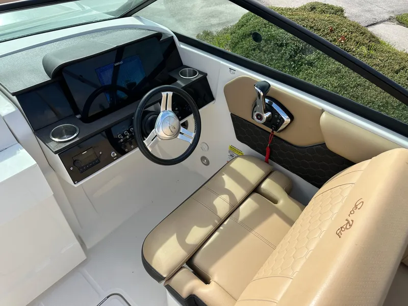 Slide: The Image of 2023 Sea Ray SDX 250 Outboard boat interior with steering wheel and beige seating. - 6