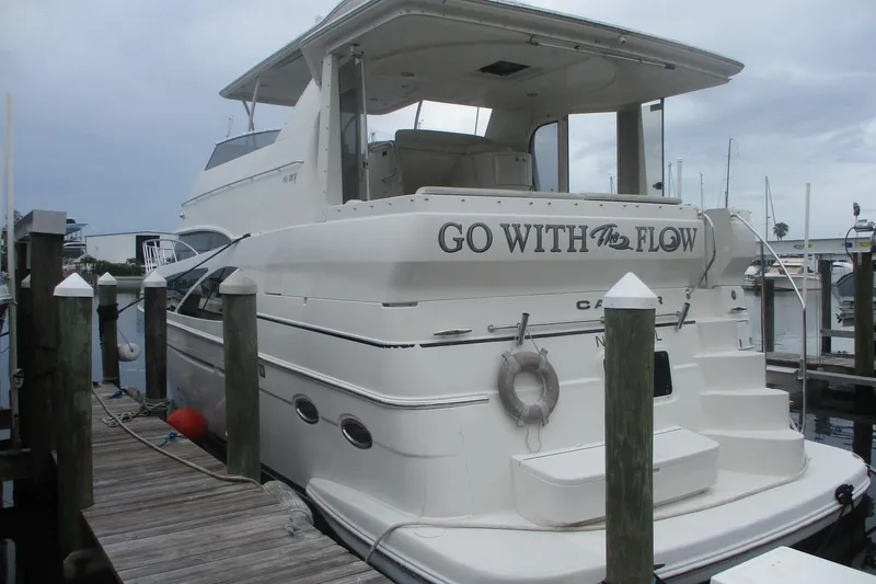 Slide: The Image of 2006 Carver 466 Motor Yacht docked, featuring "Go With The Flow" on the stern. - 2