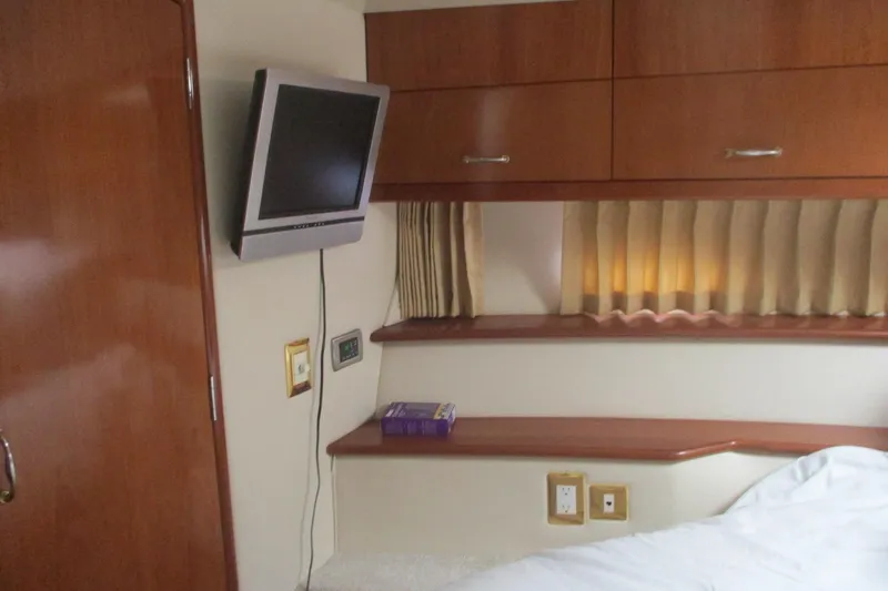 Slide: The Image of Interior of 2006 Carver 466 Motor Yacht with TV, wooden cabinets, and cozy bed. - 33