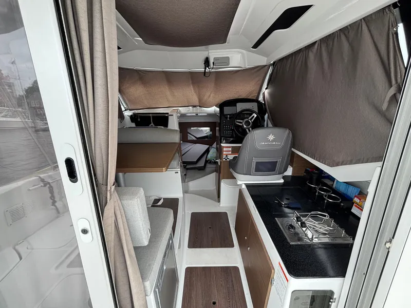 Slide: The Image of Interior of 2019 Jeanneau NC 795 boat, featuring helm, seating, and compact kitchen area. - 10