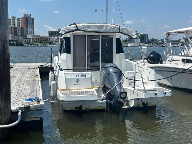 Slide: The Image of 2019 Jeanneau NC 795 boat docked at marina, rear view with outboard motor. - 2
