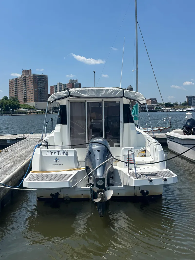 Slide: The Image of 2019 Jeanneau NC 795 boat docked at marina with cityscape background. - 3