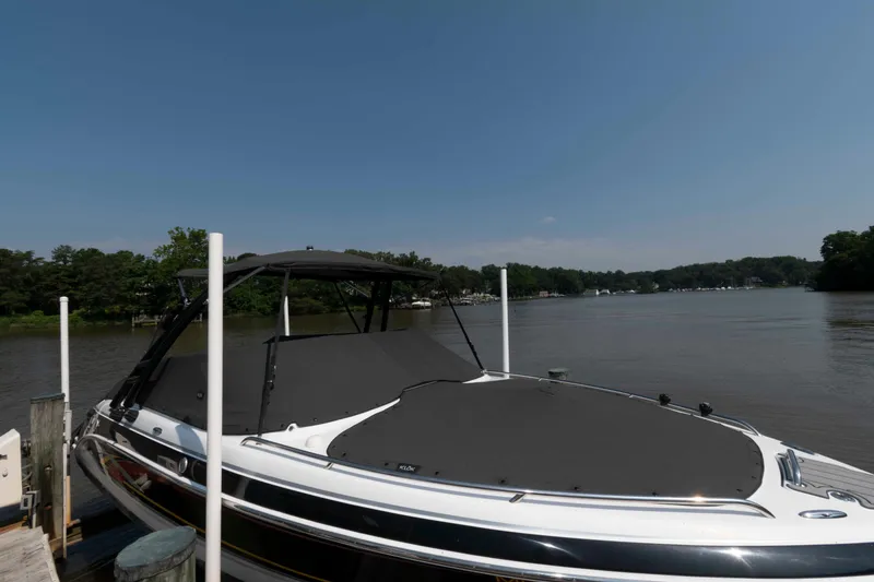 Slide: The Image of 2006 Formula 240 Bowrider boat docked on a calm lake under a clear blue sky. - 12