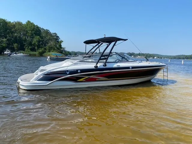 Slide: The Image of 2006 Formula 240 Bowrider boat on a calm lake with trees in the background. - 2