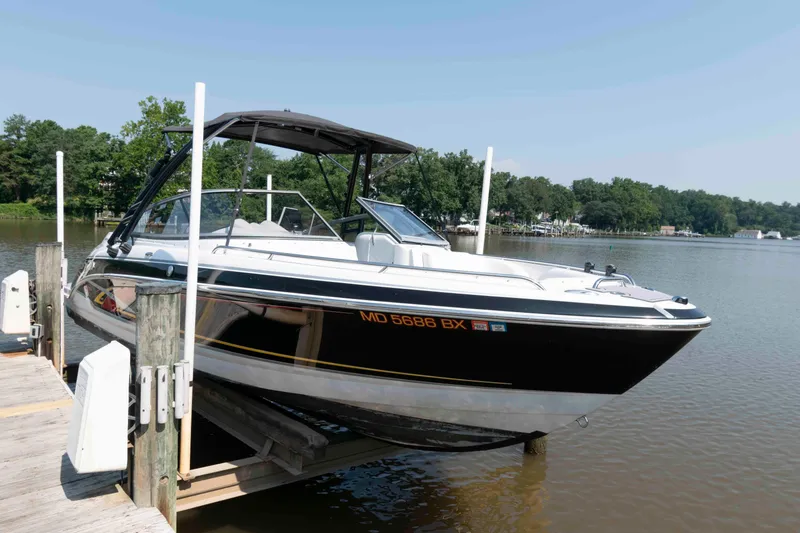 Slide: The Image of 2006 Formula 240 Bowrider boat docked on a calm lake with lush greenery. - 20