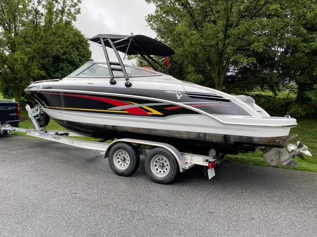 Slide: The Image of 2006 Formula 240 Bowrider boat on trailer, parked outdoors, with sleek black and red design. - 7