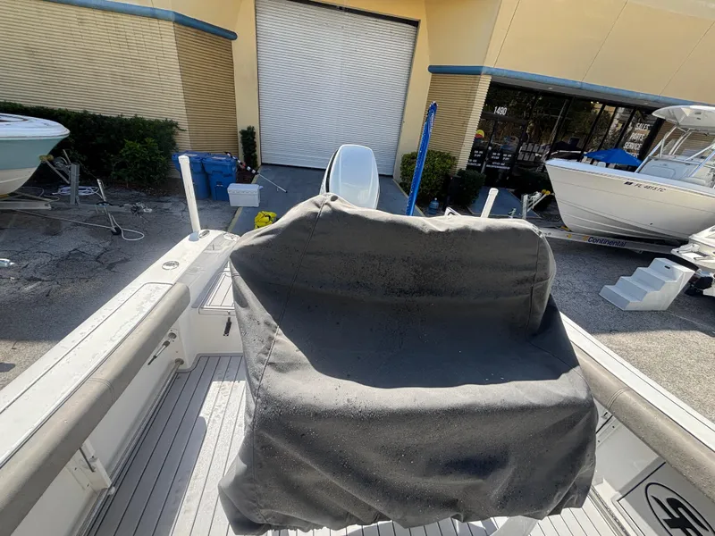 Slide: The Image of 2022 Sea Pro 239 Center Console boat with covered seating, docked near a warehouse. - 15