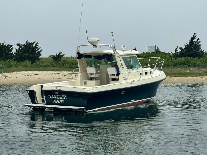 Slide: The Image of 2001 Albin 28 boat named "Tranquility" on calm water near a sandy shore. - 3