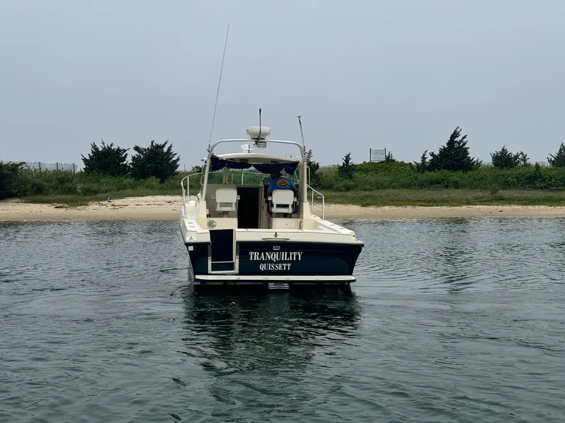 Slide: The Image of 2001 Albin 28 boat named "Tranquility" on calm water near a sandy shore. - 4