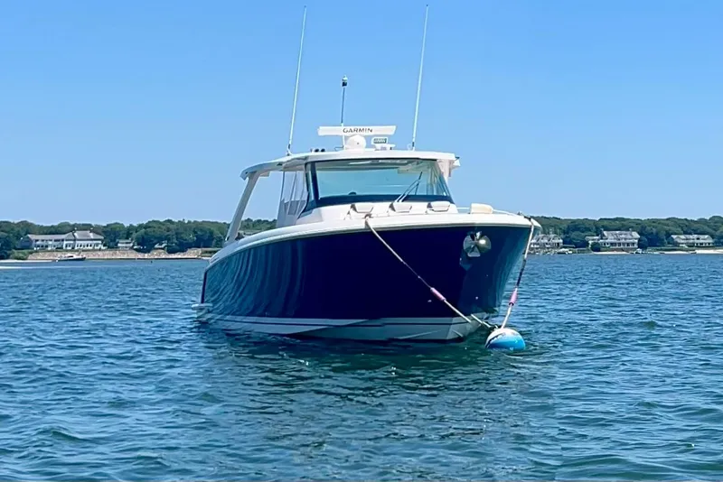 Slide: The Image of 2020 Tiara Yachts 43 LS boat anchored on calm water with shoreline in background. - 2