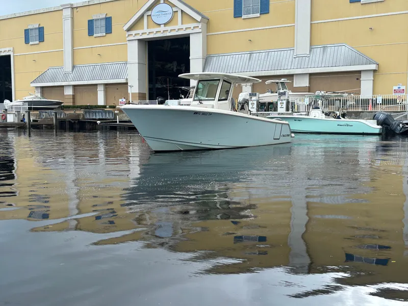 The Image of 2023 Sailfish 272 CC boat docked near a yellow building with blue shutters. - 0
