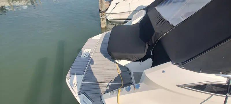 Slide: The Image of 2021 Sea Ray Sundancer 320 yacht with black cover docked on calm water. - 6