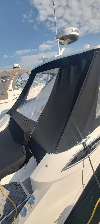 Slide: The Image of 2021 Sea Ray Sundancer 320 with black canopy, docked under a clear blue sky. - 7