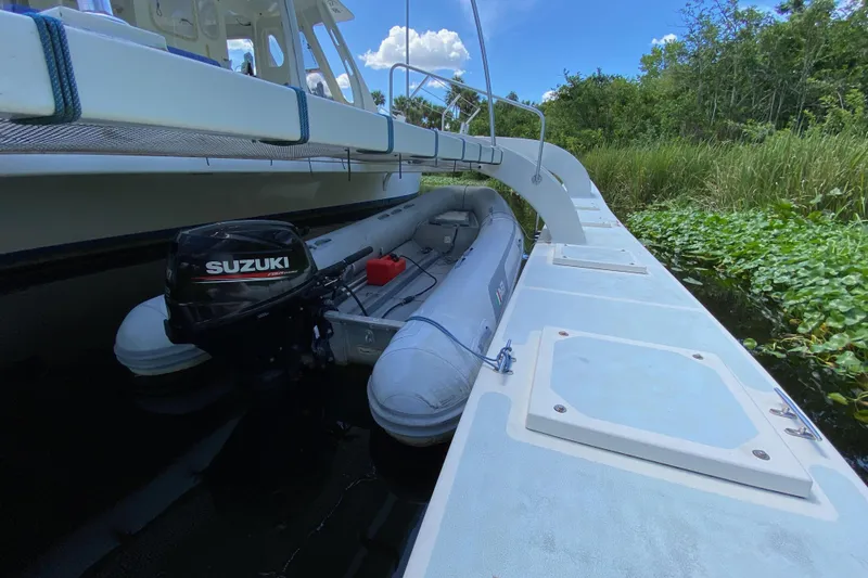 Slide: The Image of Custom 62 boat with Suzuki motor docked near lush greenery, 1996 model. - 11
