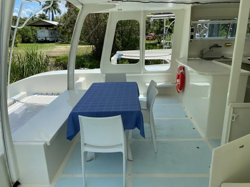 Slide: The Image of Spacious boat interior with table, chairs, and kitchenette, surrounded by lush greenery. - 24