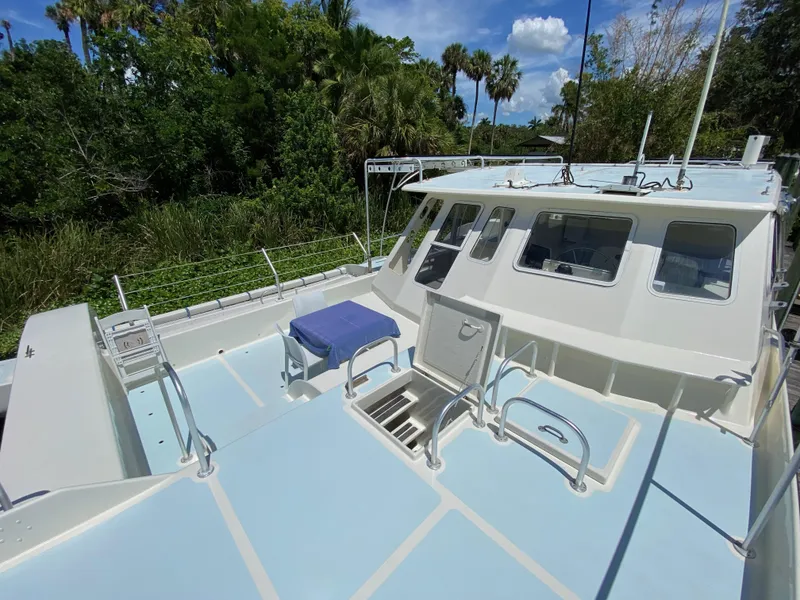 Slide: The Image of Custom 62 boat from 1996 with spacious deck, surrounded by lush greenery. - 6