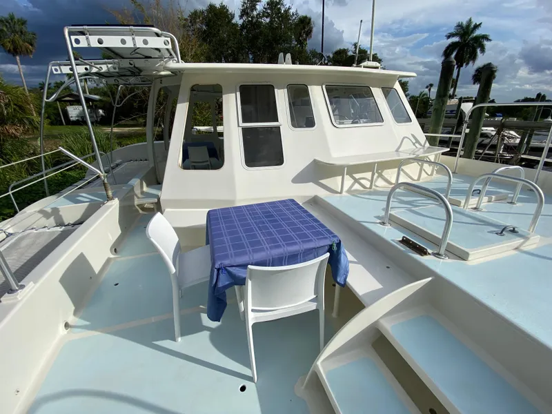 Slide: The Image of Deck of a 1996 Custom 62 boat with table and chairs, under a cloudy sky. - 7