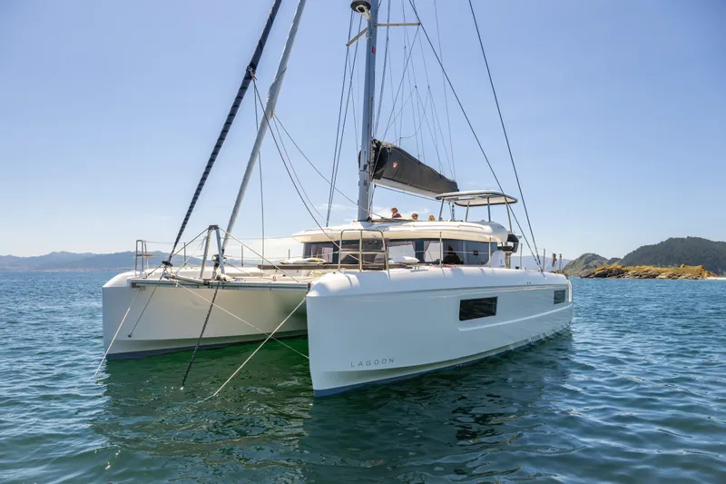 The Image of 2026 Lagoon 43 catamaran sailing on calm waters with scenic coastal backdrop. - 11