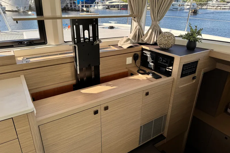 Slide: The Image of Interior of 2026 Lagoon 43 yacht with modern wooden cabinetry and electronics. - 26