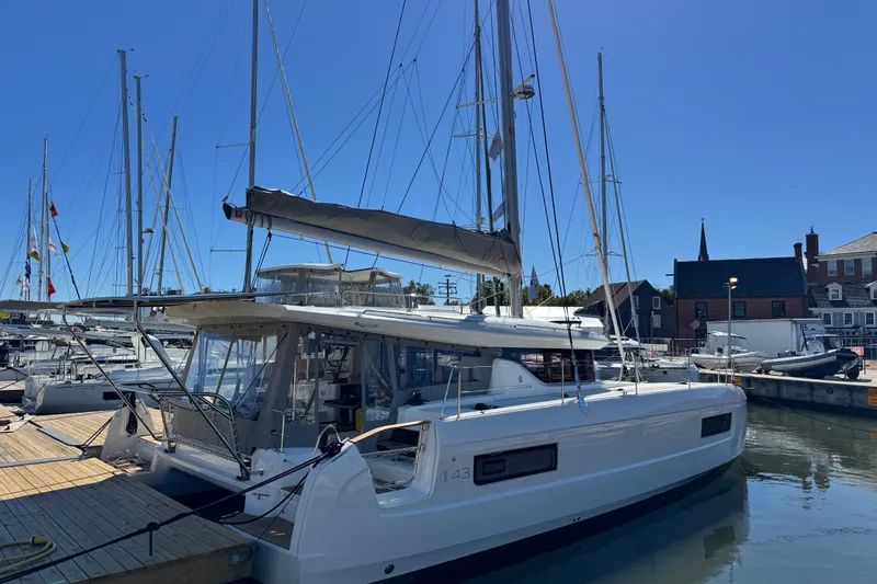 The Image of 2026 Lagoon 43 catamaran docked at marina under clear blue sky. - 0