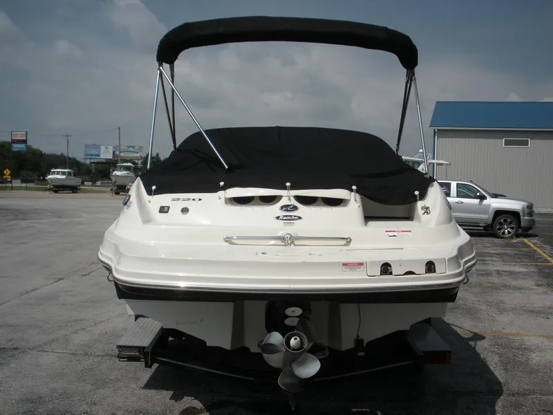 Slide: The Image of 2007 Sea Ray 220 Sundeck boat with black cover, parked on a trailer. - 2