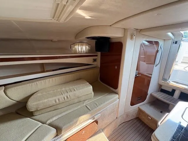 Slide: The Image of 2008 Sea Ray 270 Amberjack cabin interior with beige seating and wooden accents. - 20