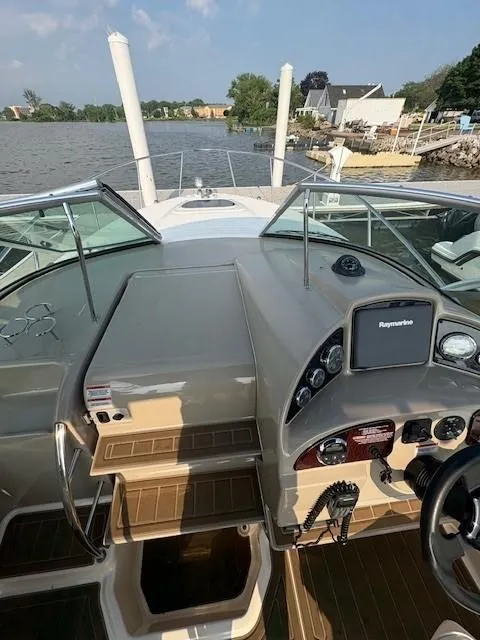 Slide: The Image of 2008 Sea Ray 270 Amberjack boat cockpit with steering wheel and navigation system, docked by a lake. - 4