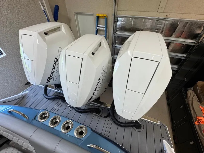 Slide: The Image of 2024 Nor-Tech 390 Sport Center Console with triple outboard engines in a garage setting. - 12