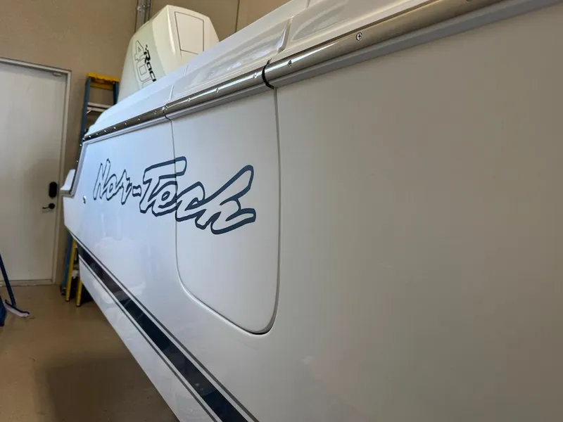 Slide: The Image of 2024 Nor-Tech 390 Sport Center Console boat side view in a garage setting. - 23