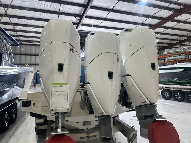 Slide: The Image of 2024 Nor-Tech 390 Sport Center Console with triple outboard engines in a boat storage facility. - 32