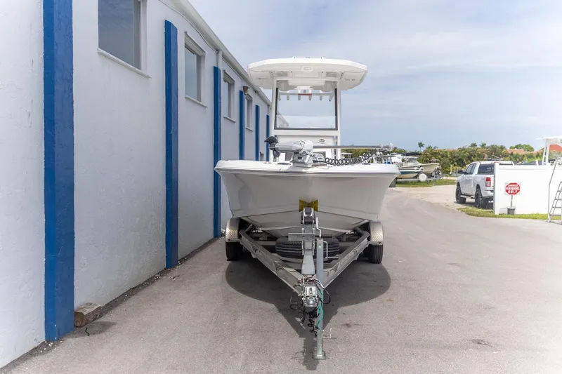 Slide: The Image of 2025 Crevalle 24 HCO boat on trailer near blue-striped building. - 11