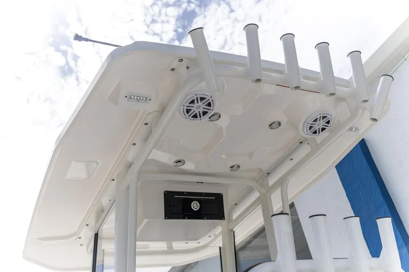 Slide: The Image of 2025 Crevalle 24 HCO boat T-top with rod holders and speakers against a cloudy sky. - 15