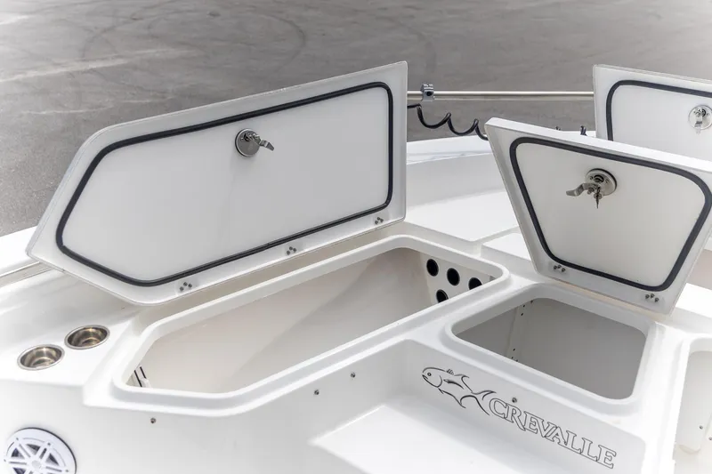 Slide: The Image of 2025 Crevalle 24 HCO boat storage compartments with open lids and secure locks. - 24